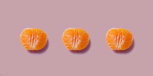 Three open halves of oranges on a purple background