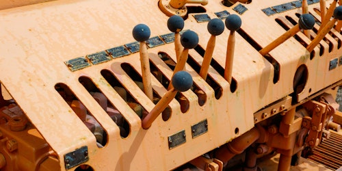 A series of levers with blue knobs on an old piece of machinery