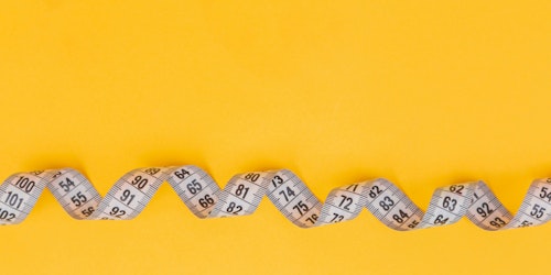 A twirled-up tape measure on a yellow background