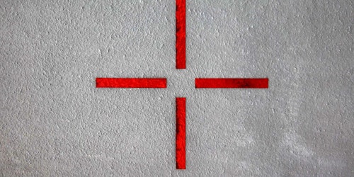 Four red lines mark a target on a grey wall