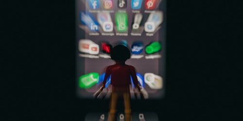 A lego man in front of a phone, showing a wall of apps, in a dreadful blur