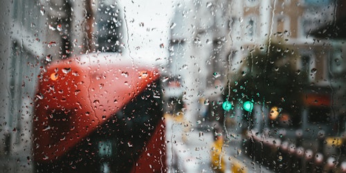 A London bus seen in front of raindrops on a window, on a winter's day