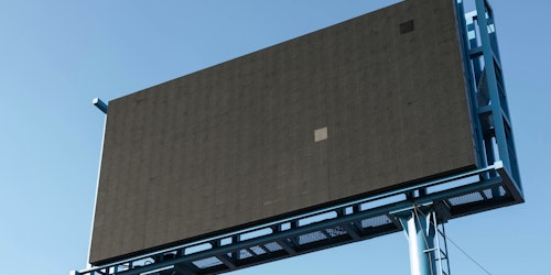 A blank digital billboard in front of a blue sky