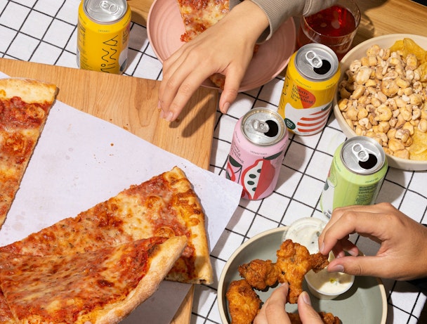 Three hands pick at different snacks laid out on a table