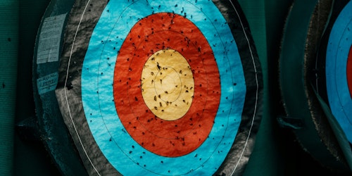 An archery target with arrow marks against a green background