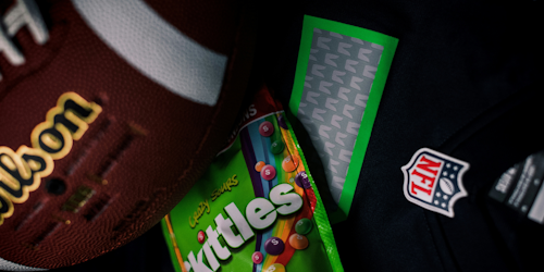 NFL logo, Wilson football and pack of sour Skittles together