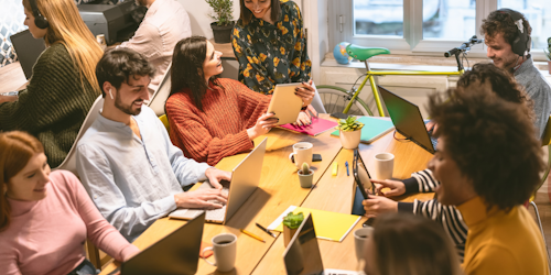 Work team sat around table on laptops